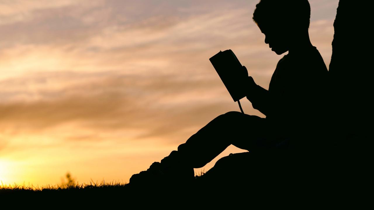 Silhouette of child reading 