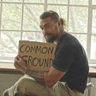 Jason Momoa holds sign reading "Common Ground"