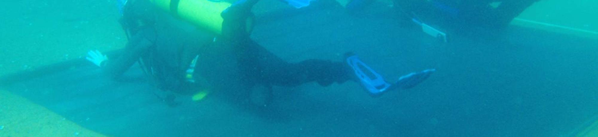Research divers placing rubber barrier mats on the lake bottom